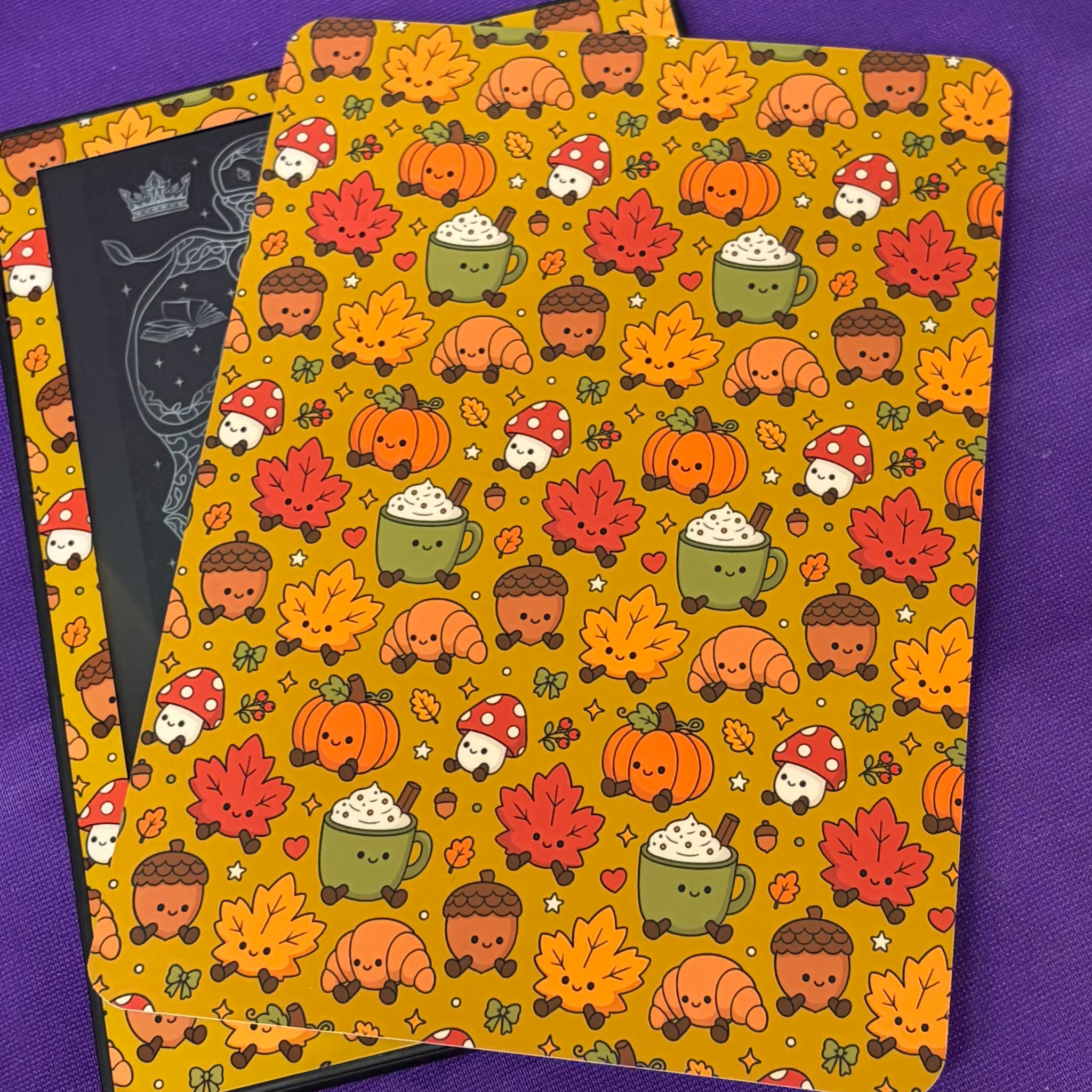 Mustard yellow Kindle backing insert patterned with pumpkins, autumn leaves, acorns, mushrooms, croissants and warm drinks
