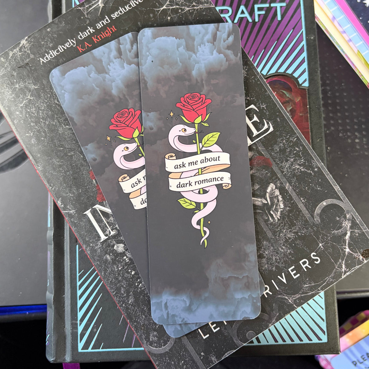 Dark cloudy bookmark featuring a pale pink snake wrapped around a red rose and an Ask Me About Dark Romance banner
