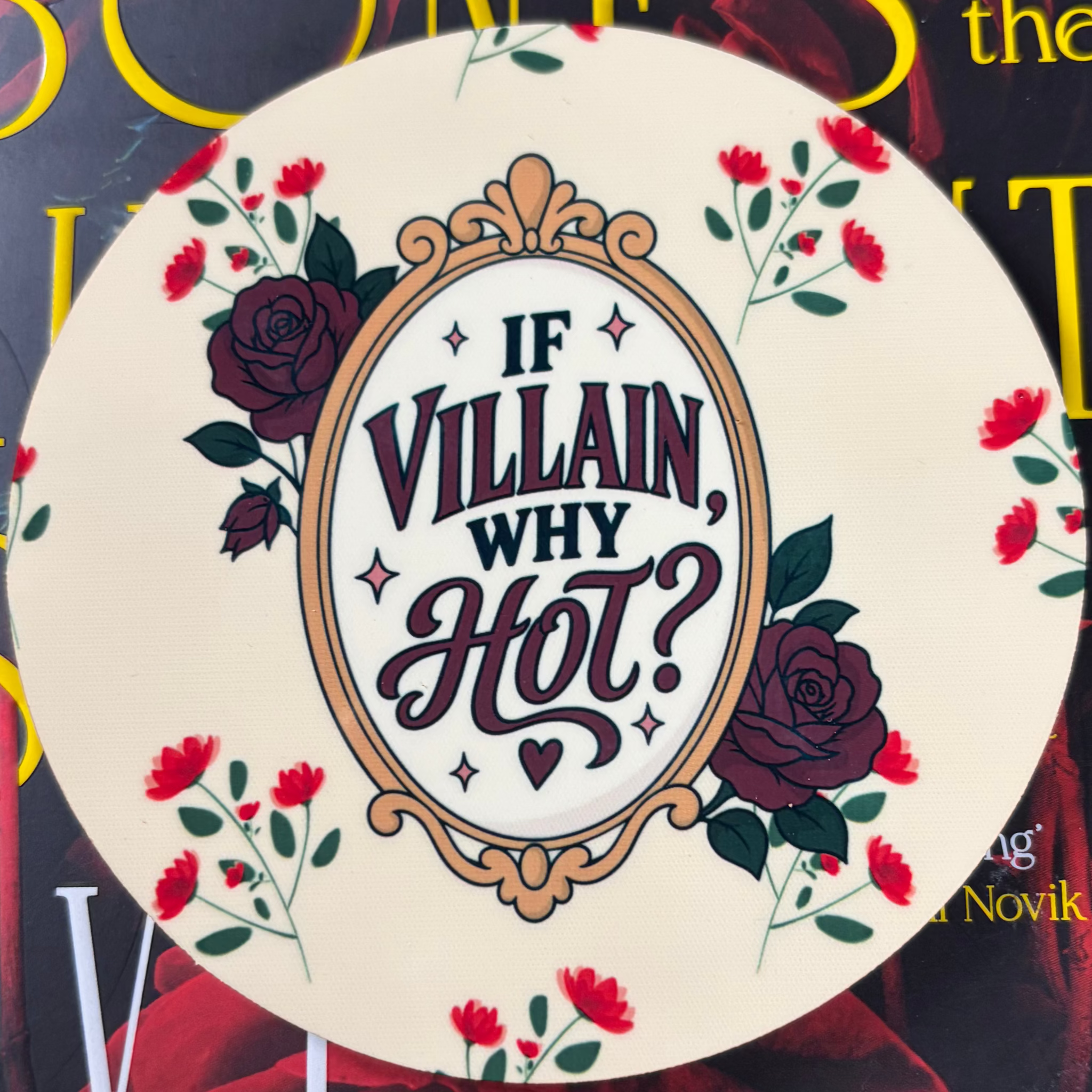 Round cream coaster with If Villain Why Hot lettering inside an ornate gold frame surrounded by burgundy and red roses
