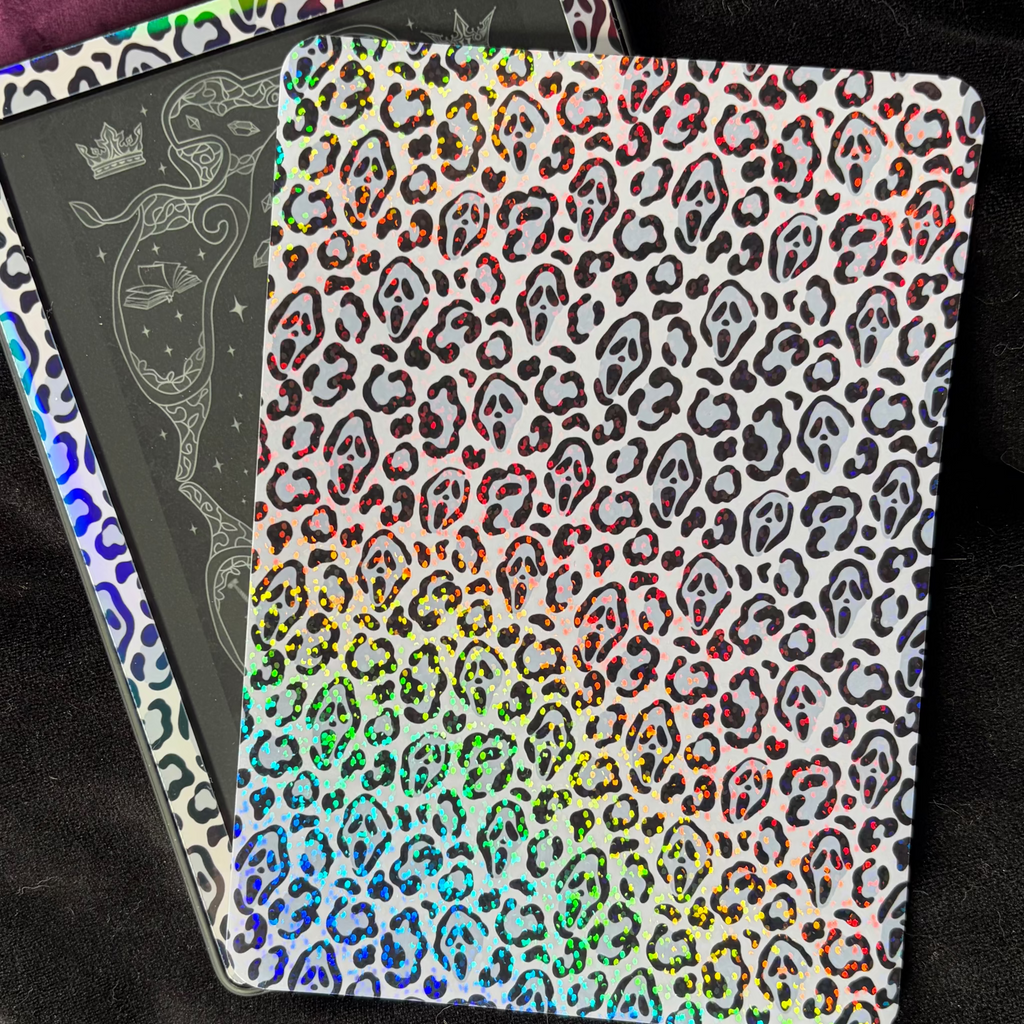 Black and grey Spooky Cheetah Kindle backing insert with hidden masked faces and a multicoloured glitter finish
