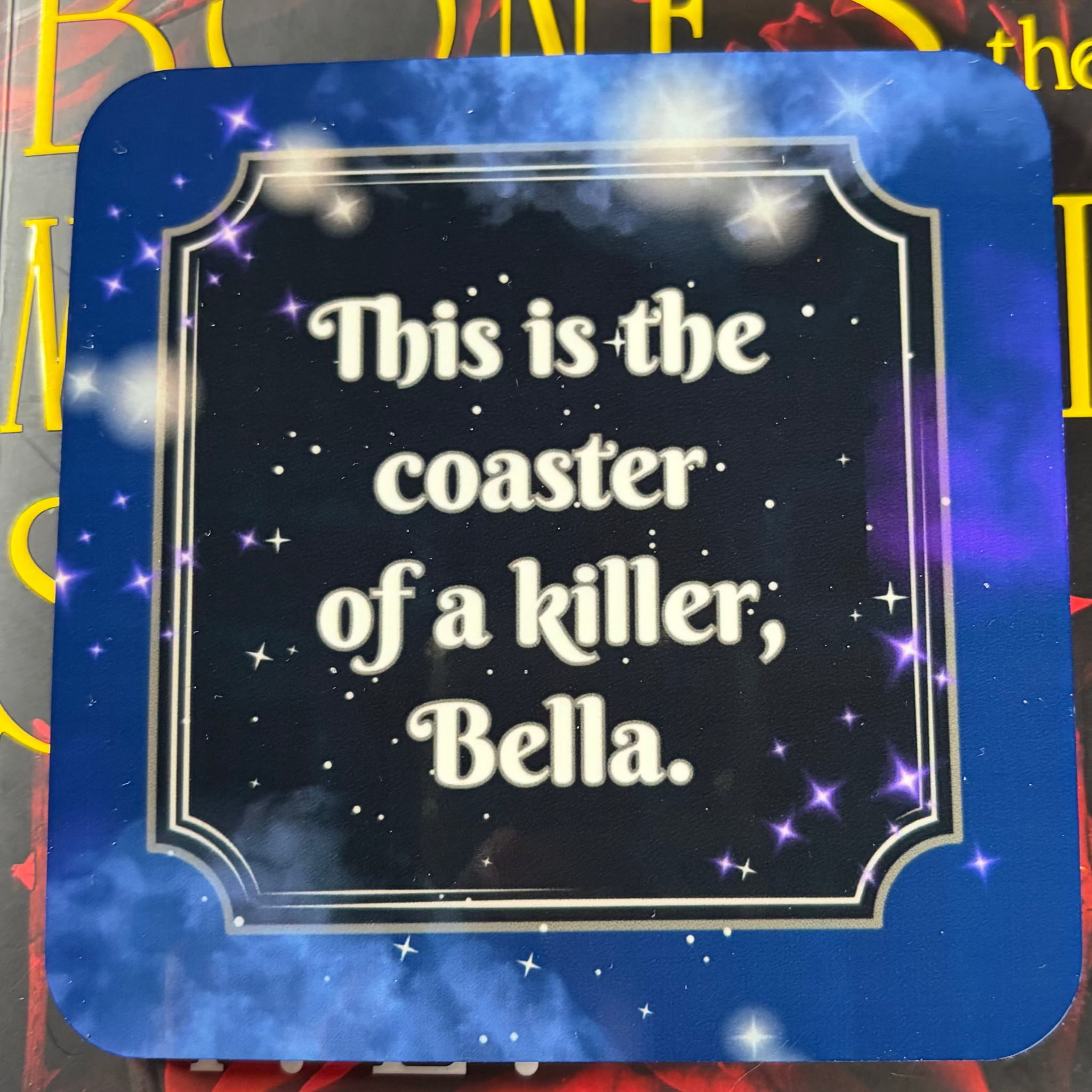 Square blue and purple galaxy coaster featuring the words This is the coaster of a killer, Bella
