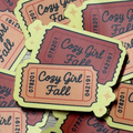Ticket-shaped Cosy Girl Fall sticker in peach, burgundy and pale yellow with an autumn leaf border