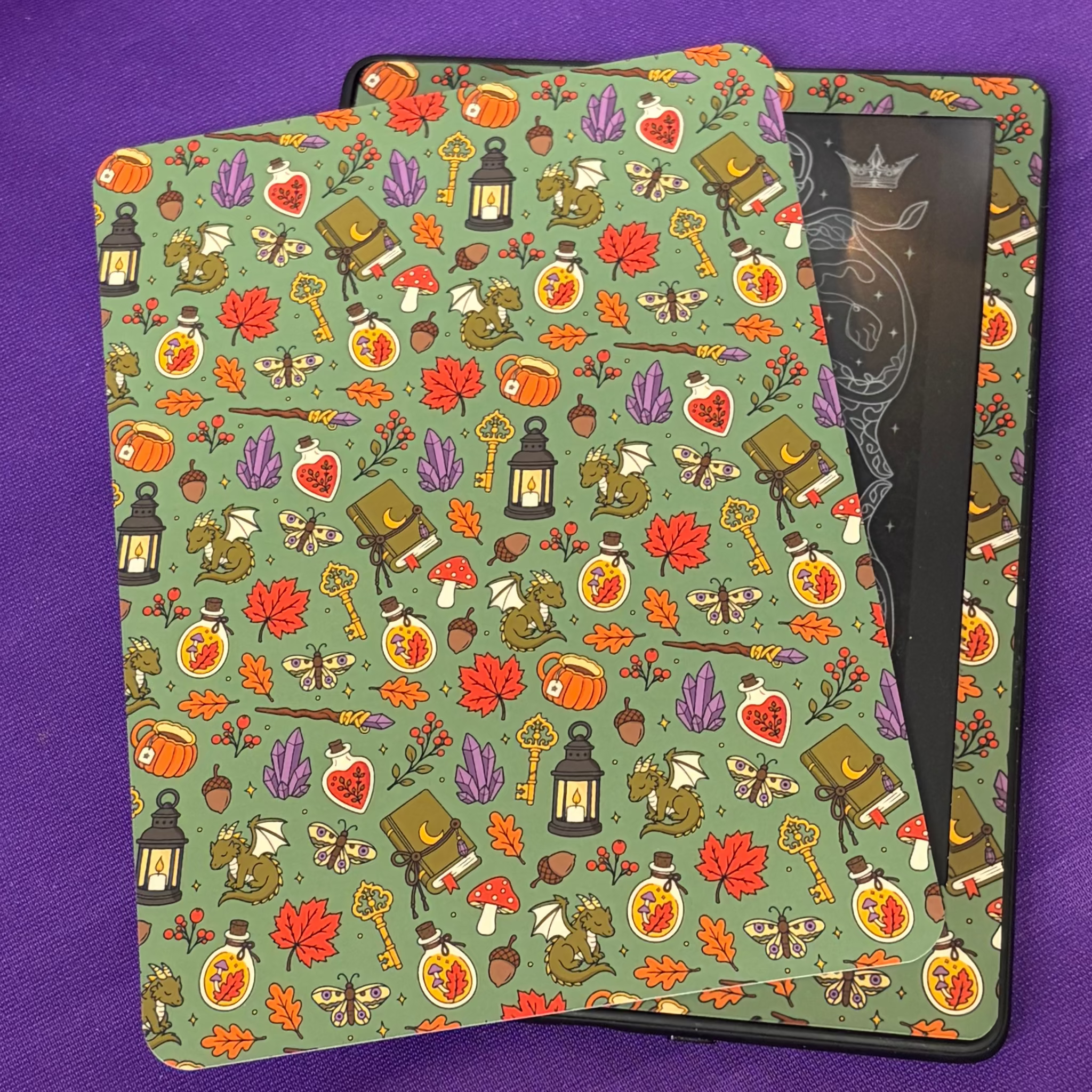 Green Witchy Woodland Autumn Kindle backing insert patterned with foxes, books, lanterns, potion bottles, mushrooms, keys and autumn leaves
