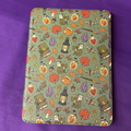 Green Witchy Woodland Autumn Kindle case patterned with mushrooms, leaves, potion bottles, books, moths and keys
